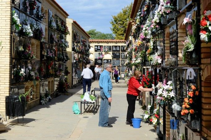 Gent posant flors al cementeri en Tots Sants