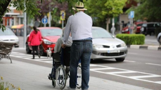 Un home passeja al costat d'un altre en cadira de rodes