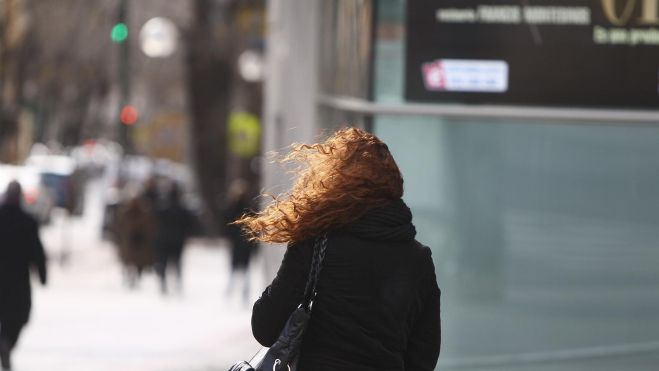 Una mujer camina por la calle en un día de viento