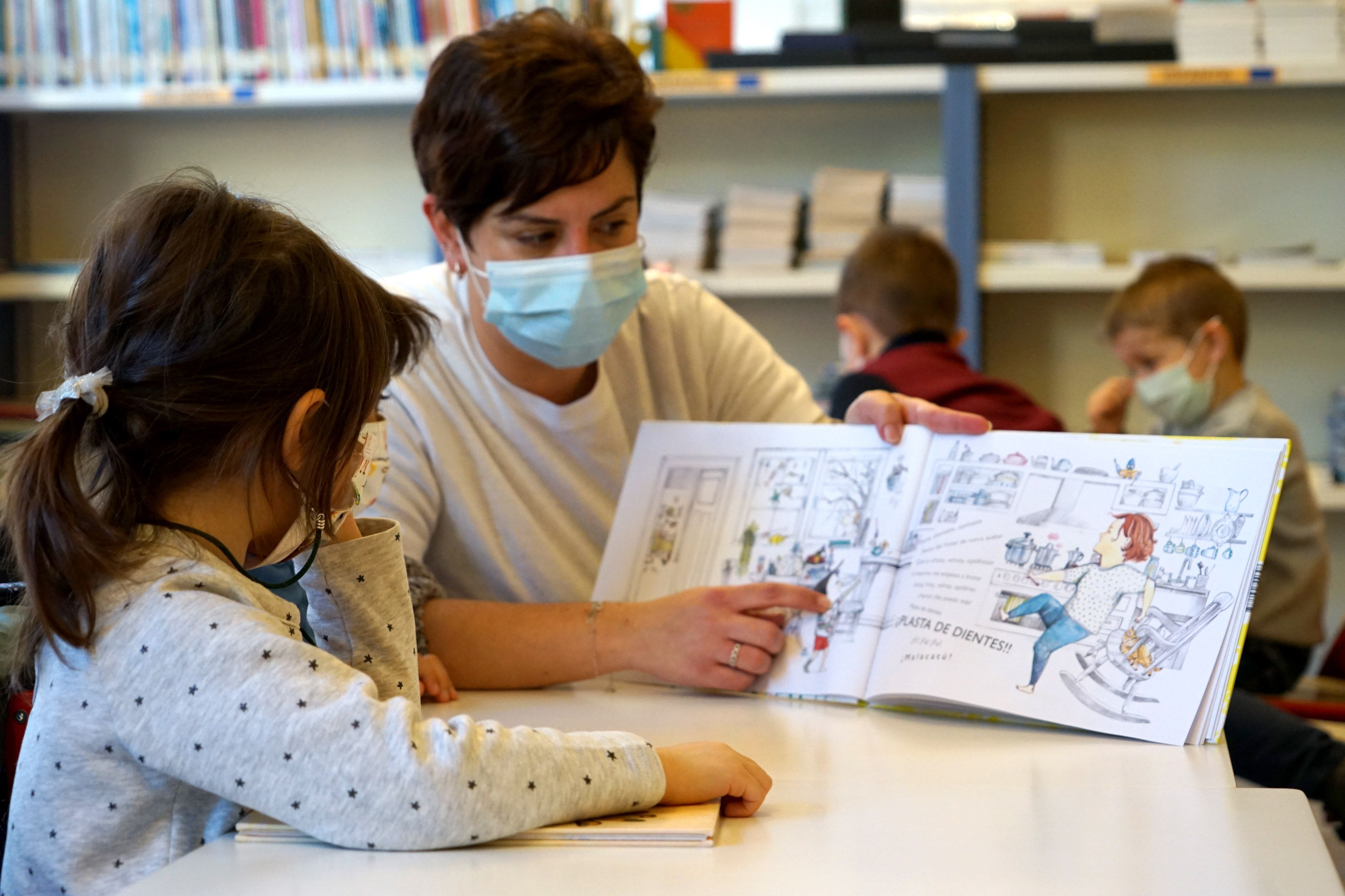 Una xiqueta llig un llibre a la biblioteca
