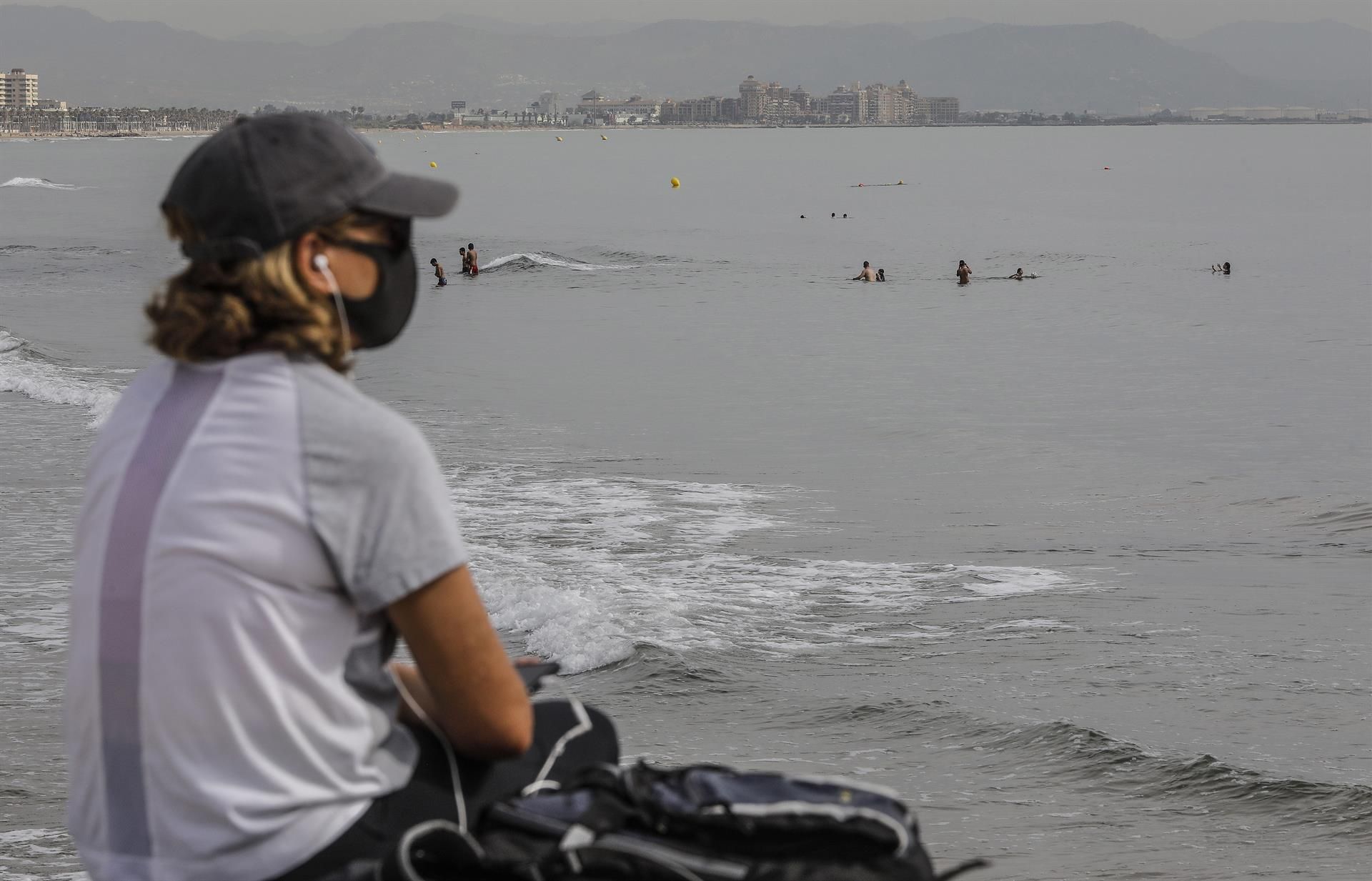 Una mujer con mascarilla en la playa