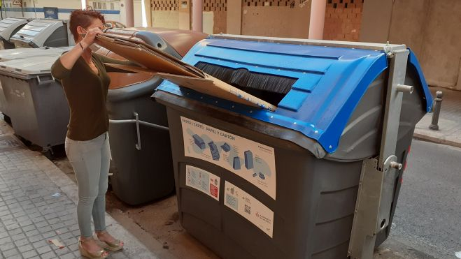 Una mujer reciclando en el contenedor azul