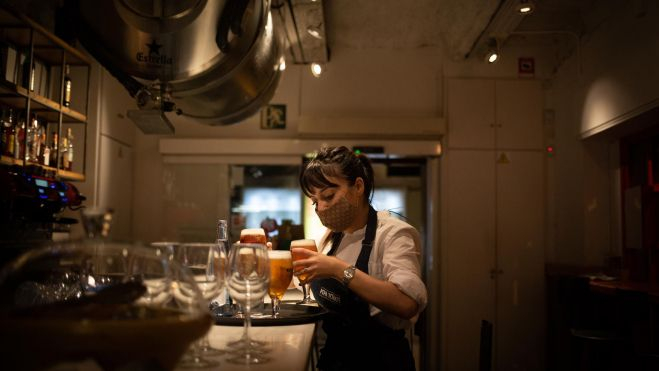 Una cambrera serveix una cervesa a l'interior d'un bar