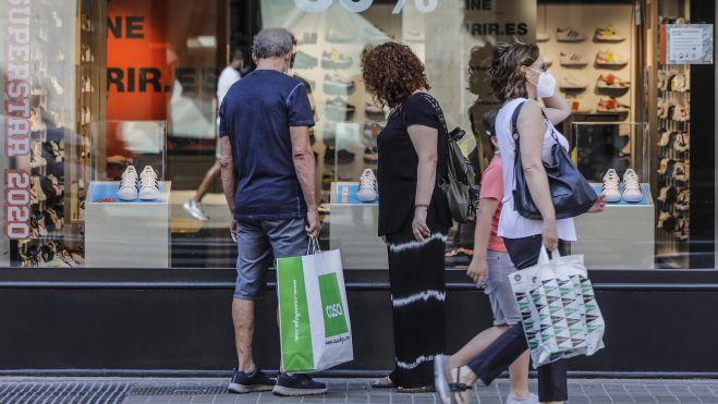 Varias personas observan objetos del escaparate de un comercio