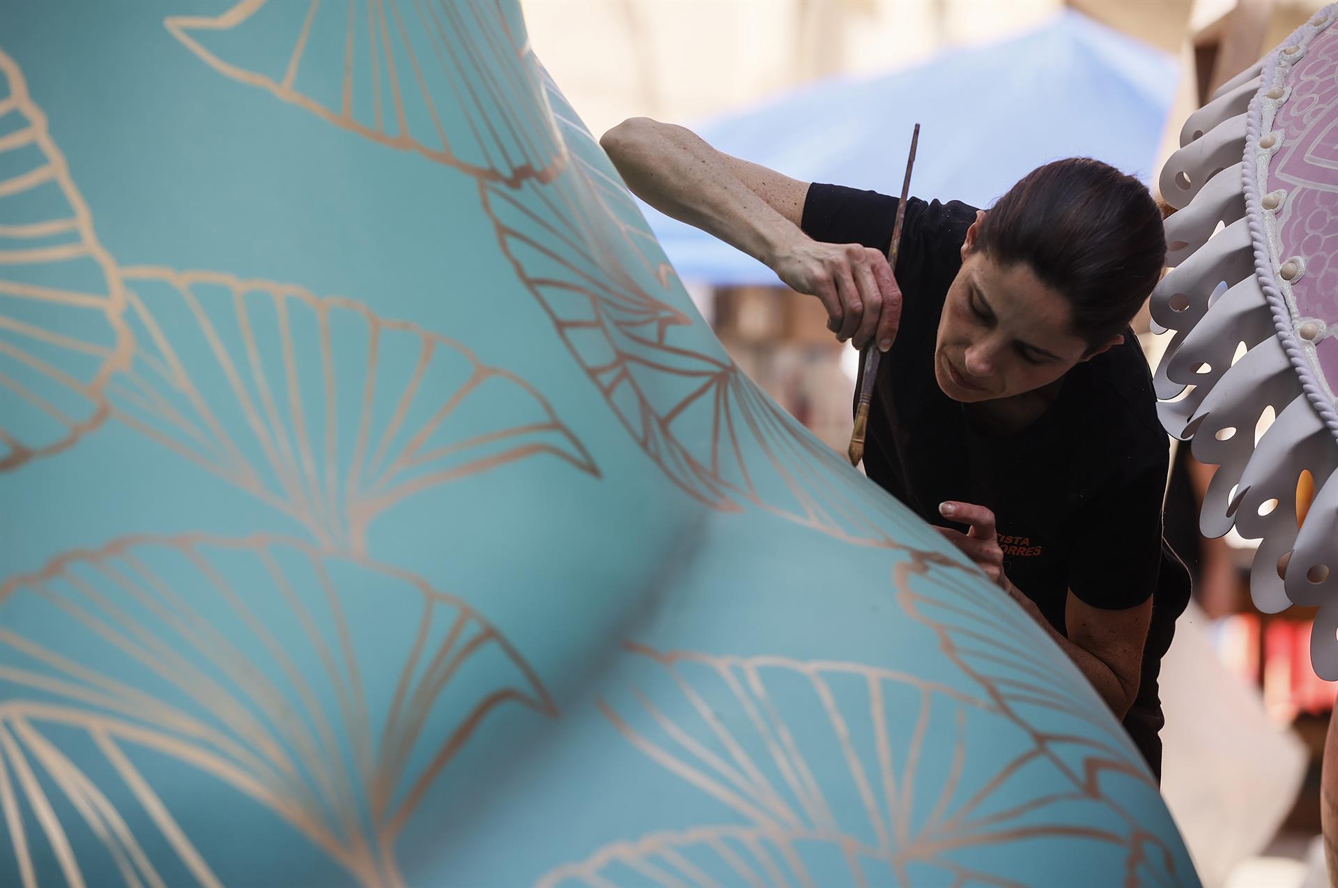 Una artista fallera ultima els detalls d'una falla.