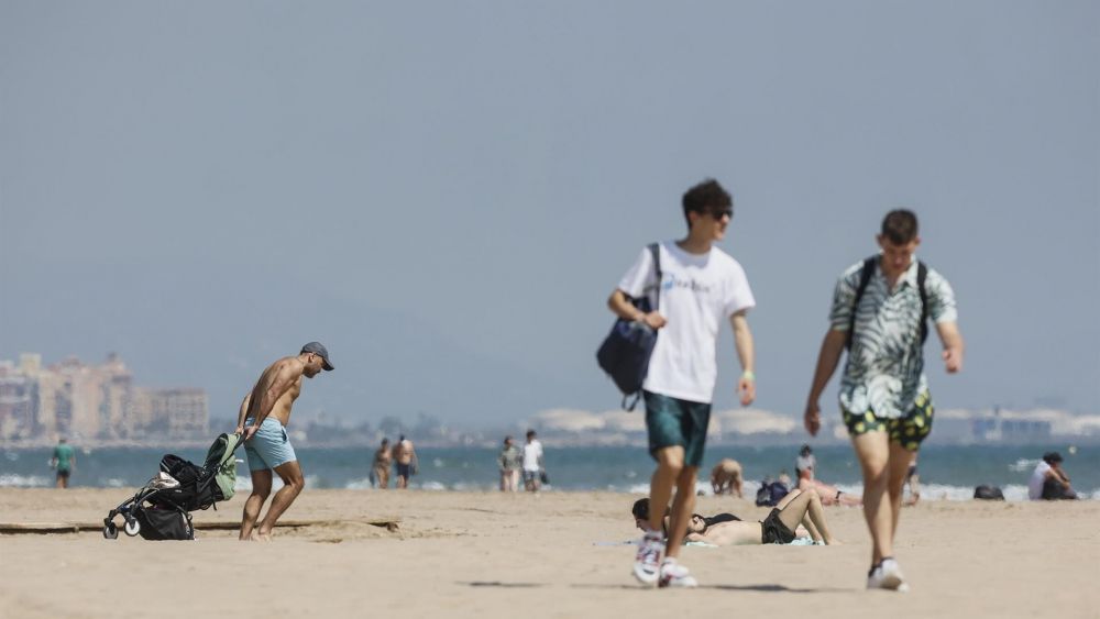 Diverses persones caminen per la platja de la Malva-rosa de València. Imatge de Rober Solsona
