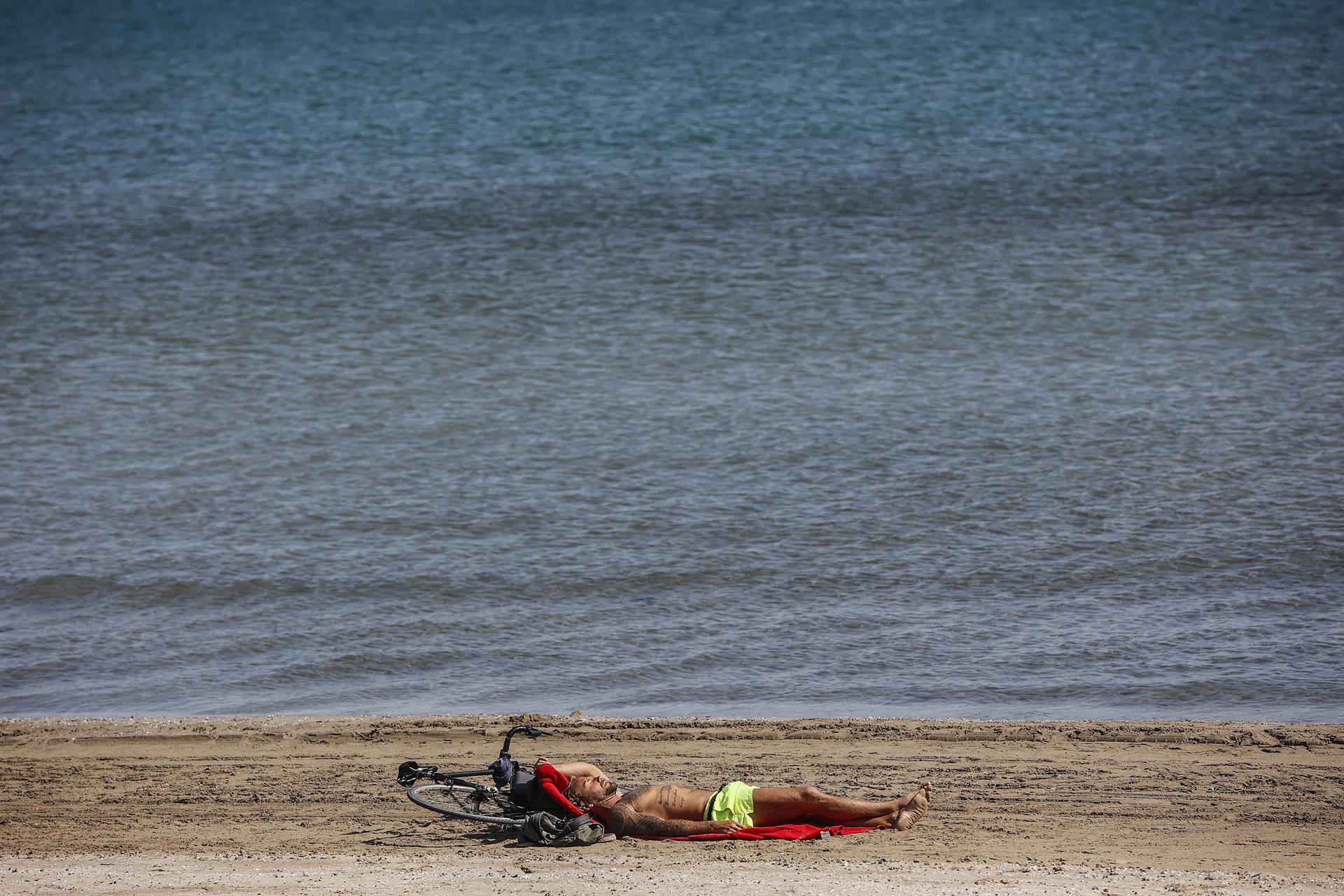 Un home tombat al costat del mar. Imatge: Rober Solsona - Europa Press