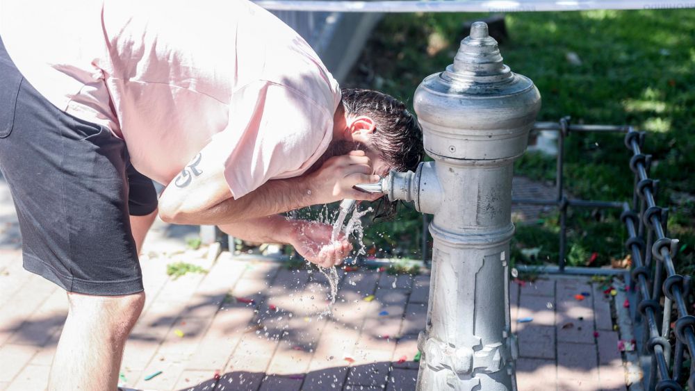 Una persona se refresca en una fuente por el calor Una persona se refresca en una fuente por el calor