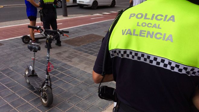  Un agent de la Policia Local de València al costat d'un patinet elèctric