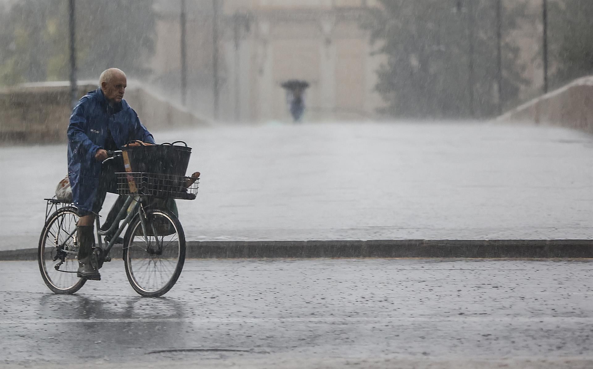 Una persona en bici bajo las lluvias en València