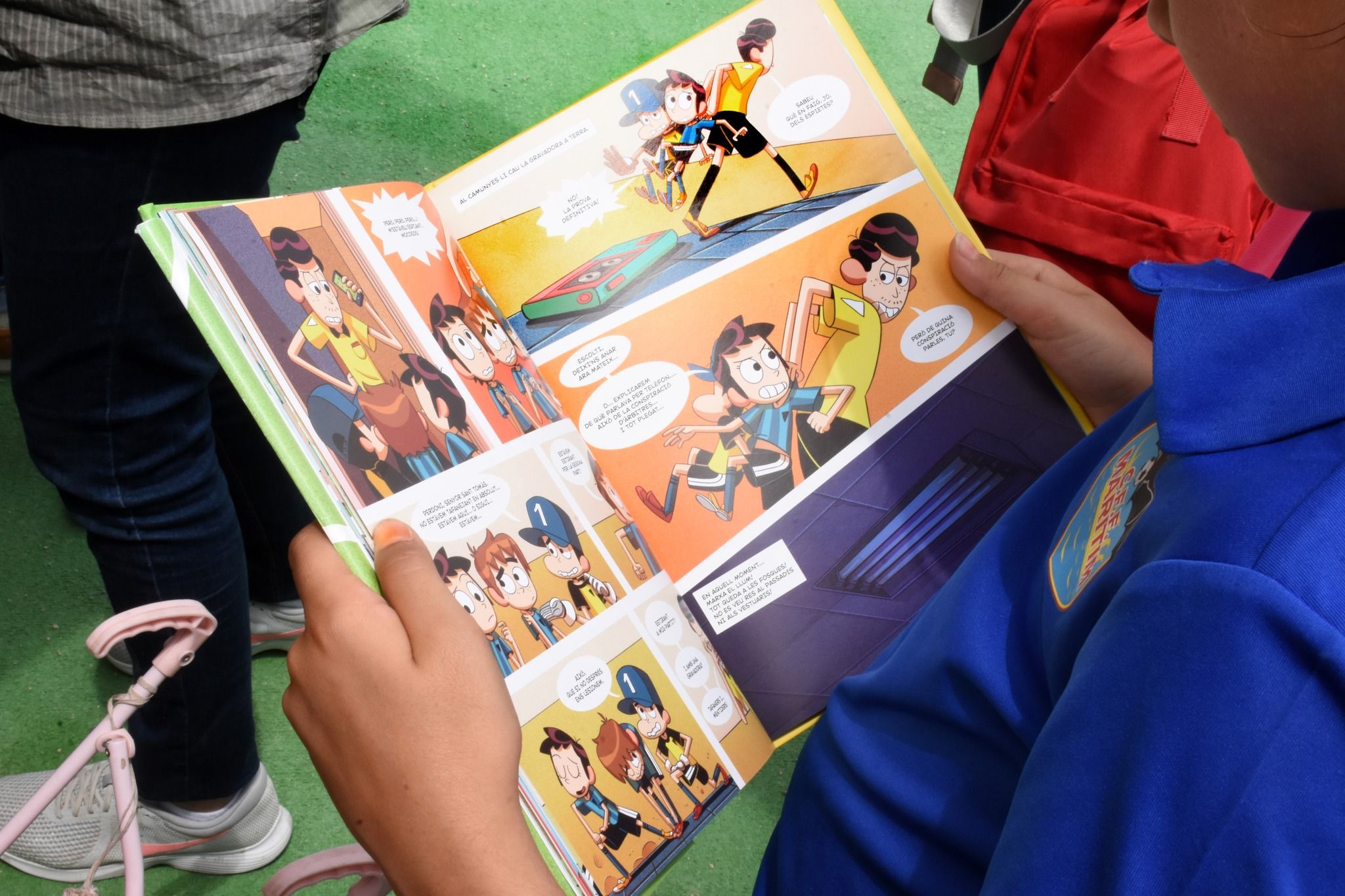 Un xiquet llig un còmic en la Fira del Llibre de València