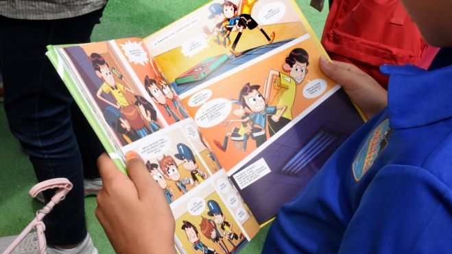Un niño lee un comic en la Feria del Libro de València