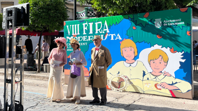 Tres personas vestidas de época se fotografían en la Feria Modernista de Carcaixent