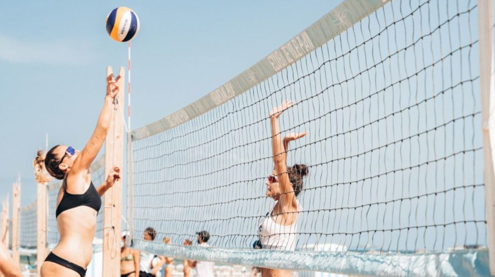 Persones jugant al voley a la platja