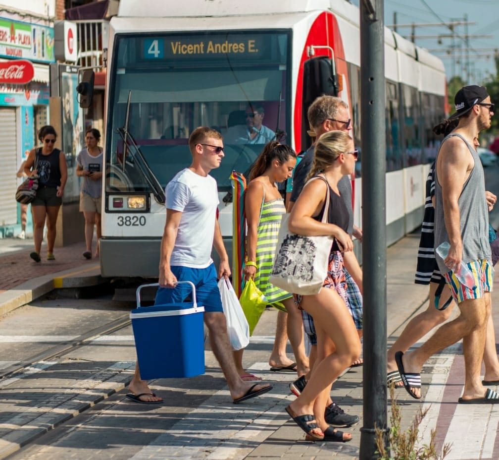 Un grupo de personas llega a la playa de Valencia en un tranvía de Metrovalencia