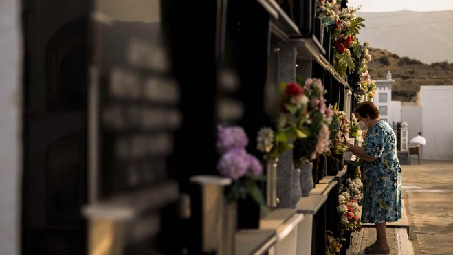 Una mujer pone en flores en el cementeri Una dona posa flors en el cementeri