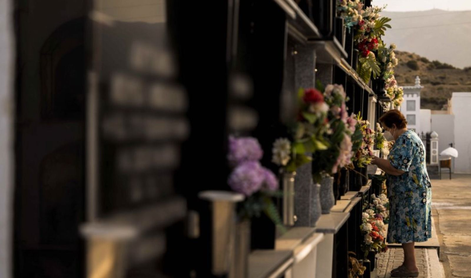 Una mujer pone en flores en el cementerio