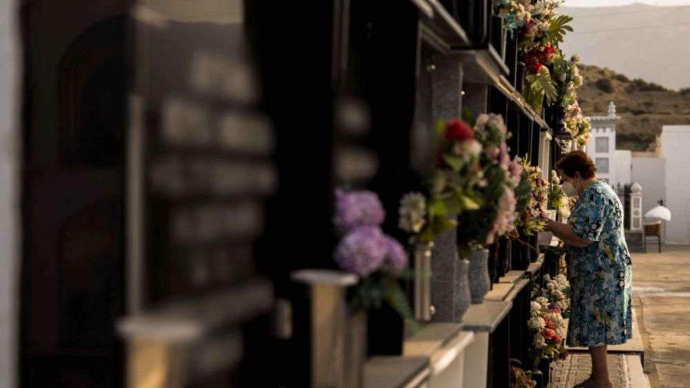 Una mujer pone en flores en el cementeri Una dona posa flors en el cementeri