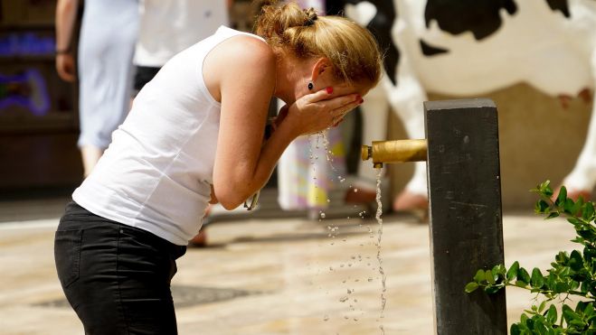 Una mujer se refresca en una fuenta por la ola de calor Una mujer se refresca en una fuenta por la ola de calor