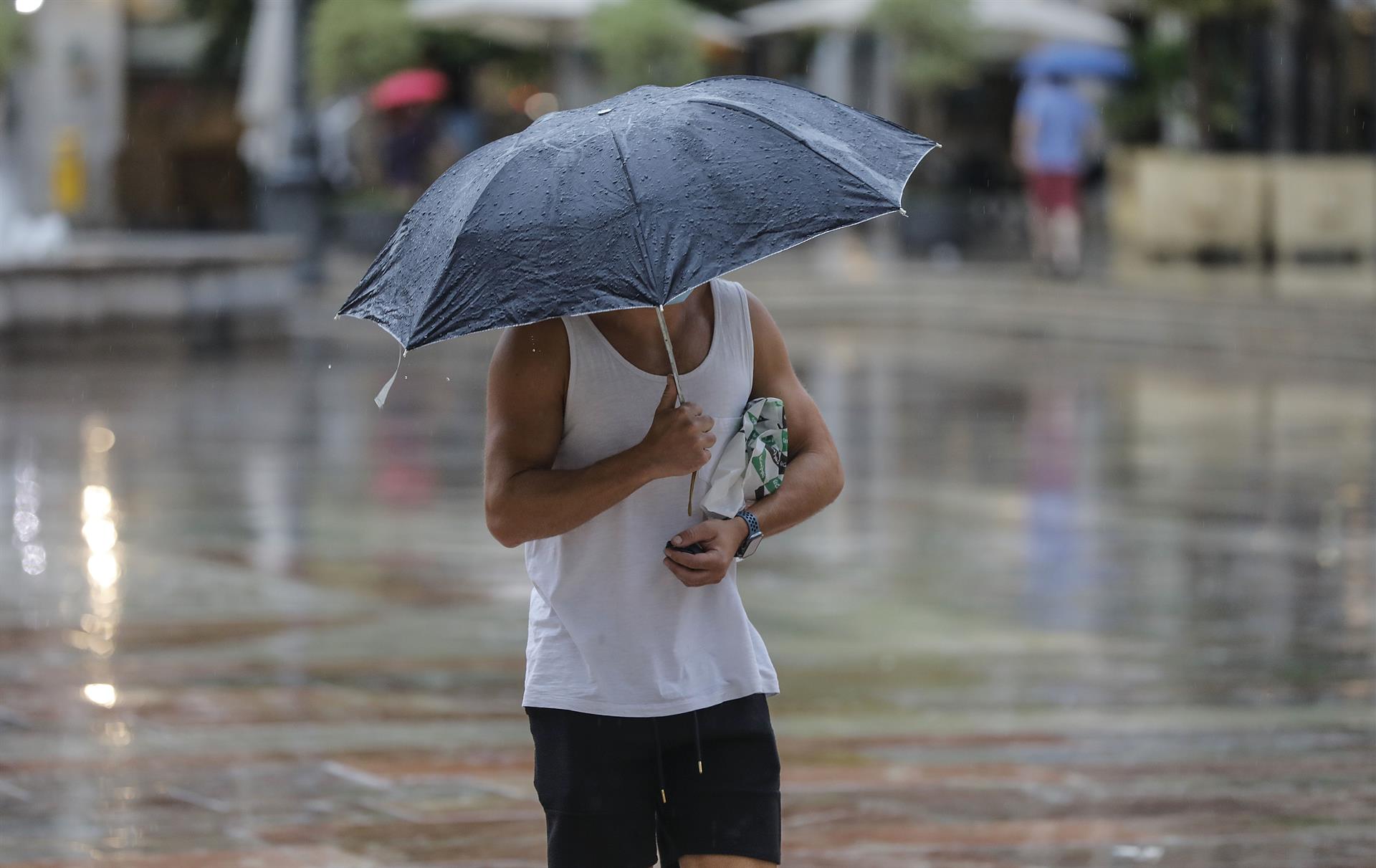 Una persona con paraguas por las lluvias del verano