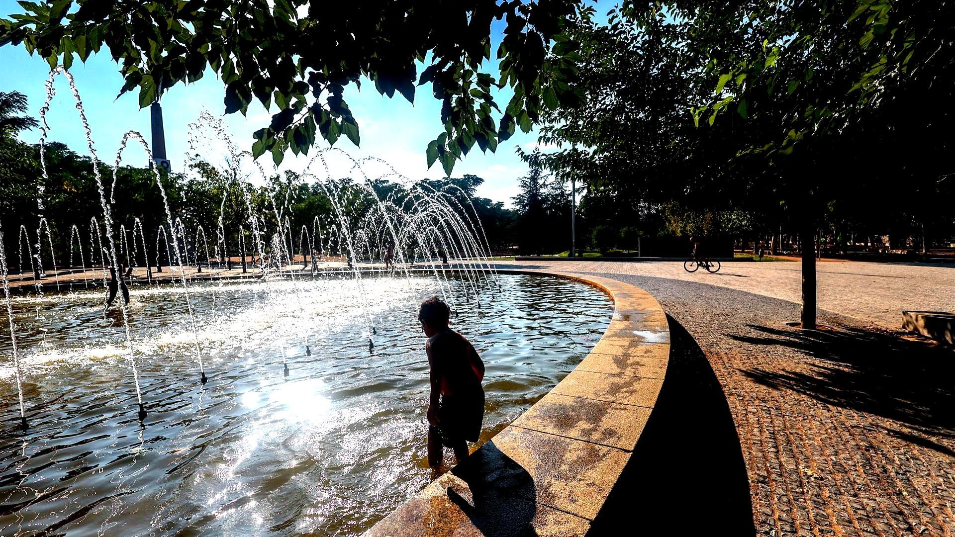 Un niño refrescándose en la fuente ante la ola de calor