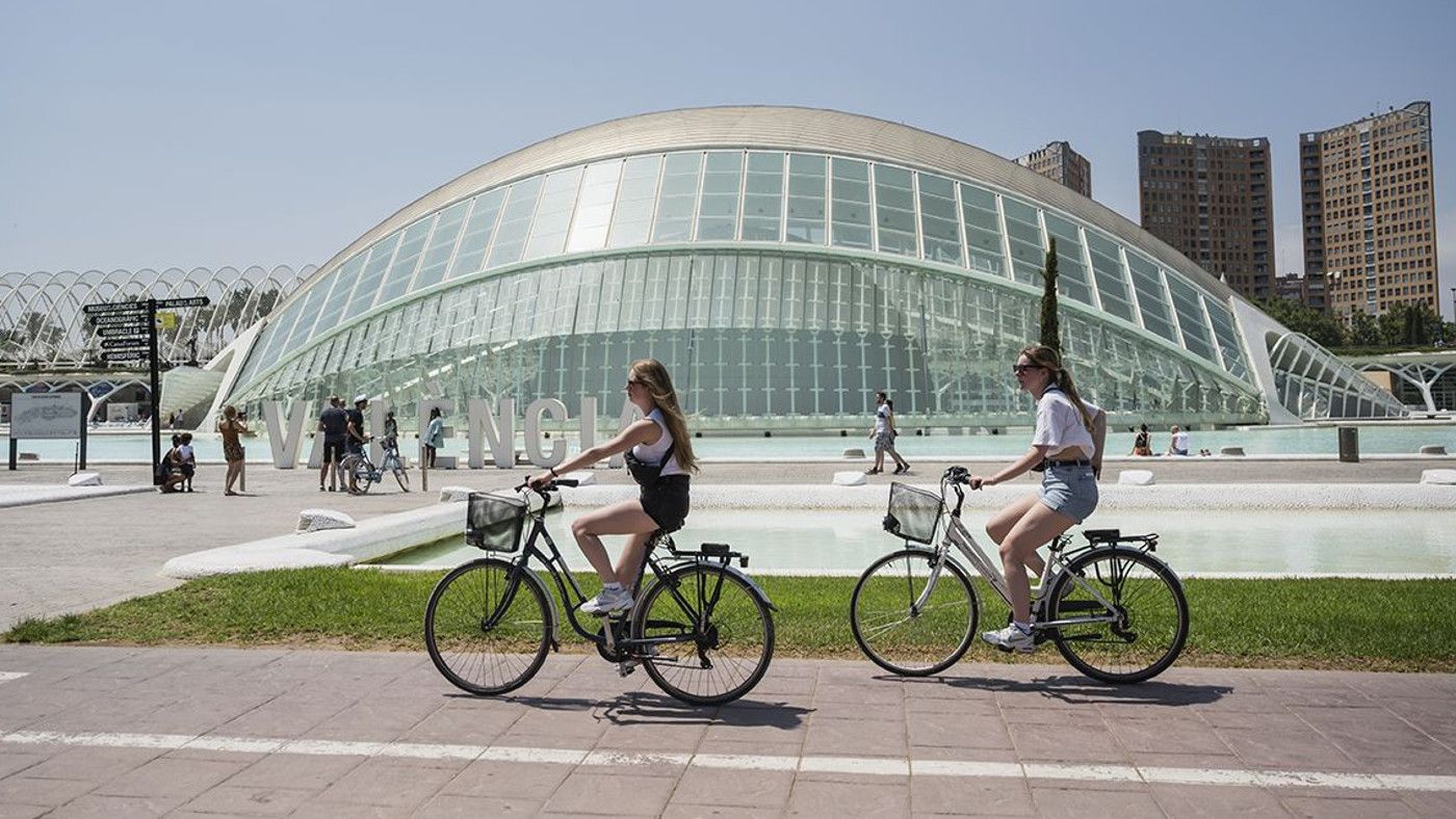 Unas turistas, con bicicleta, por la Ciutat de les Arts i les Ciències de València Unas turistas, con bicicleta, por la Ciutat de les Arts i les Ciències de València
