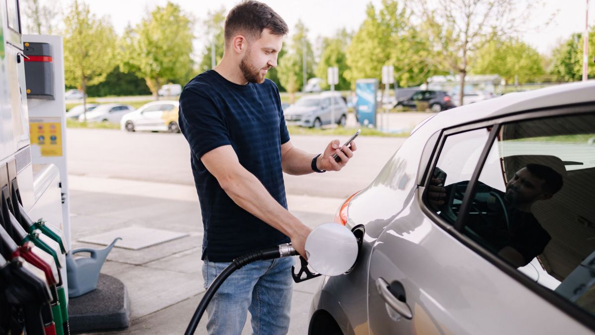 Un home utilitzant el mòbil mentres posa combustible en el seu vehicle - GettyImages Un home utilitzant el mòbil mentres posa combustible en el seu vehicle - GettyImages