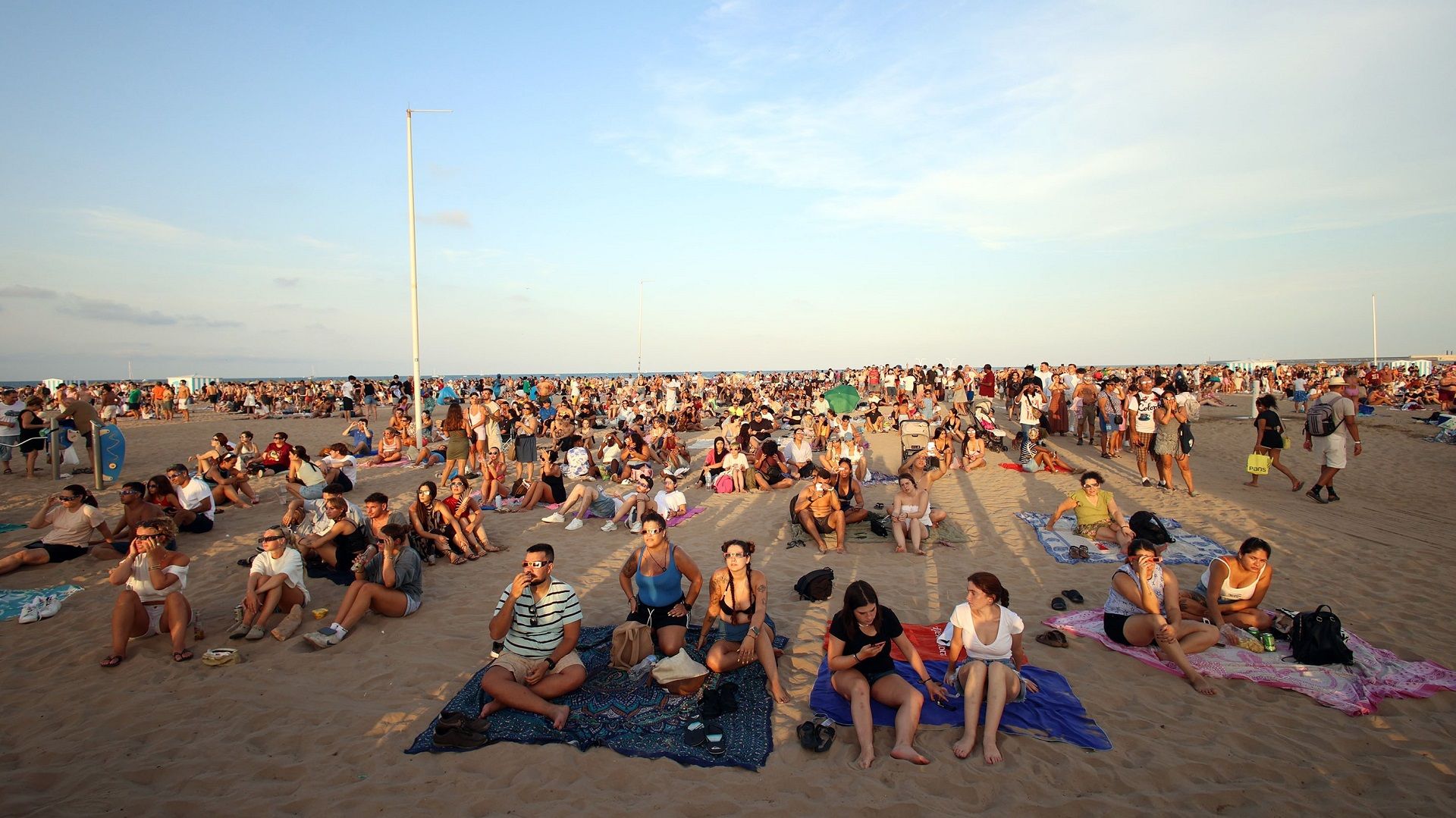 Gent en la platja de València veient l'eclipsi